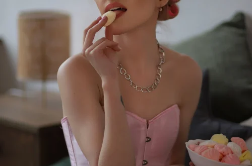 Feminine adult posing in a white corset indoors